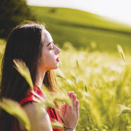 woman-meditating-palms-together-in-field