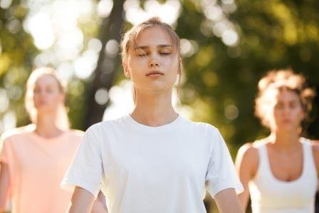 Group of young women practicing yoga, morning meditation in nature at the park. meditation retreats 2