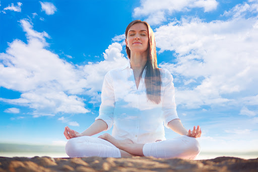 A woman sitting under the blue sky and practicing Buddhist meditation for beginners.