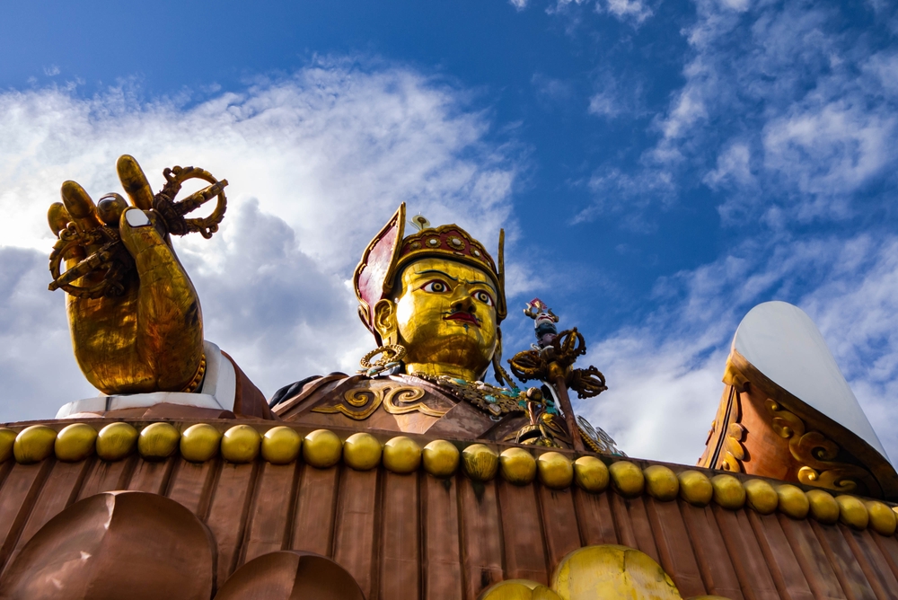 A statue of Guru Rinpoche under the blue sky.