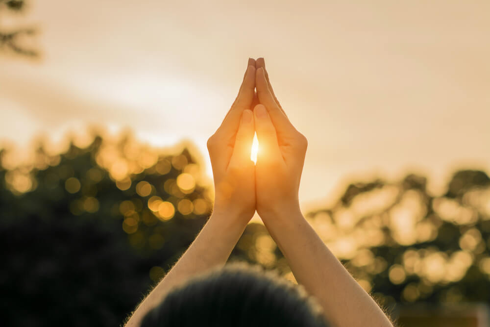 Someone practicing Buddhist meditation and praying under the sun.