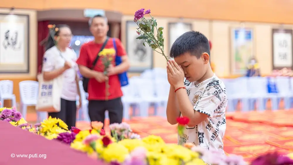 A young boy offering flowers and praying to the Buddha during the Buddha Bathing Festival.