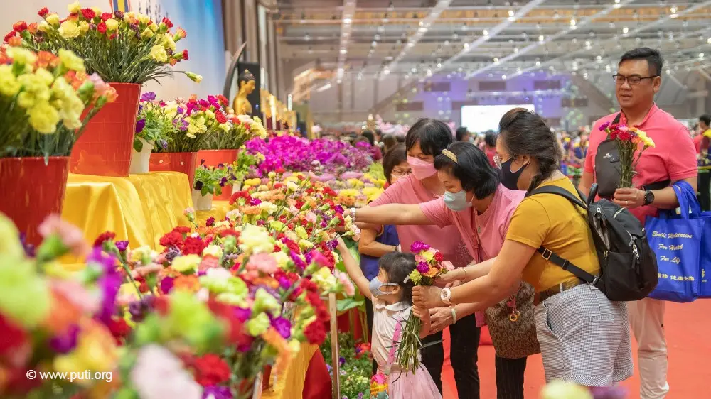 A family participating in the Buddha Bathing Festival, offering flowers before the Buddha.