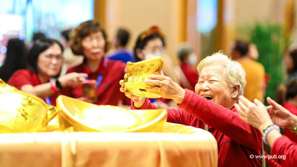 An elderly person joyfully holding a gold ingot.