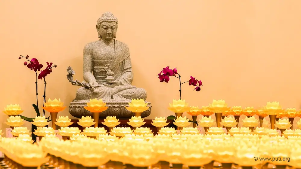 A statue of the Buddha before the lotus light-offering.