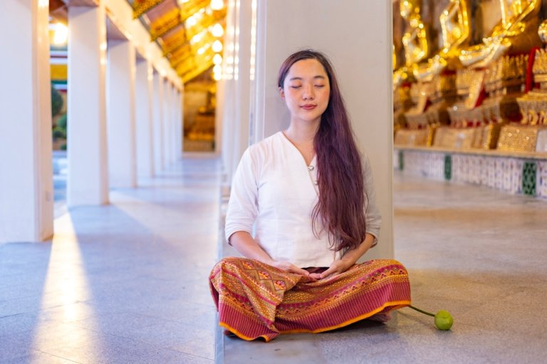 Buddhist asian woman in traditional cloth is doing mindfulness meditation in Buddhist temple for peace and tranquil religion practice concept