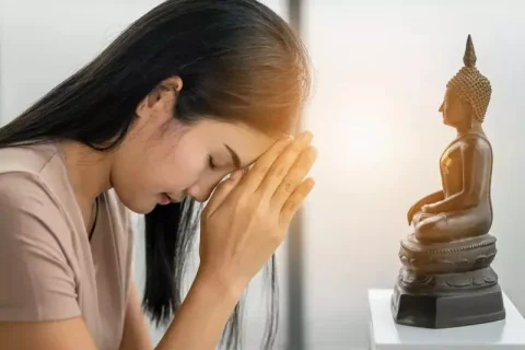 A woman worshipping and praying in front of a Buddha statue