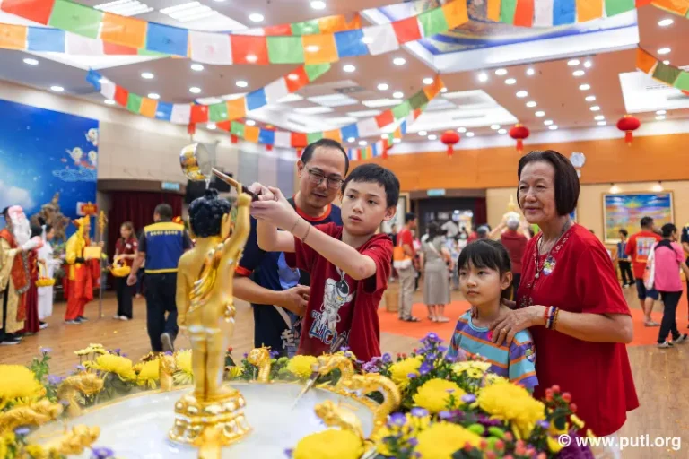 Families participate in bathing the Buddha activity together, smiling with sincerity and devotion