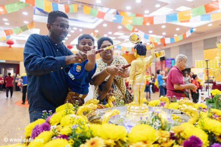 Families participate in bathing the Buddha activity together, smiling with sincerity and devotion