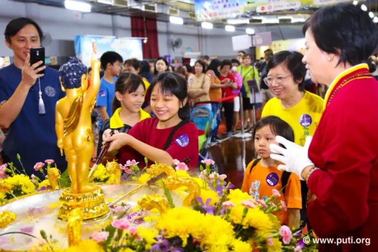 Families participate in bathing the Buddha activity together, smiling with sincerity and devotion