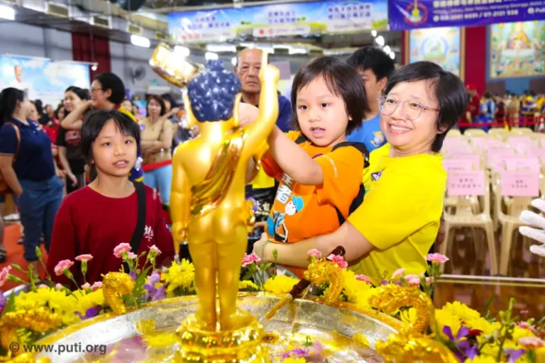 Families participate in bathing the Buddha activity together, smiling with sincerity and devotion